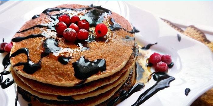Hotové palacinky s čokoládovou omáčkou a bobuľami na tanieri