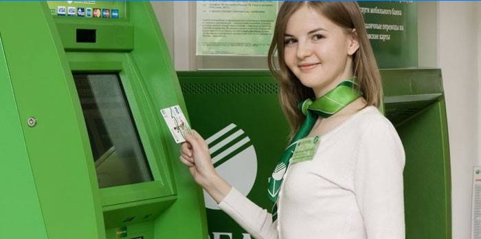 Zamestnanec Sberbank s kartou v ruke pred terminálom