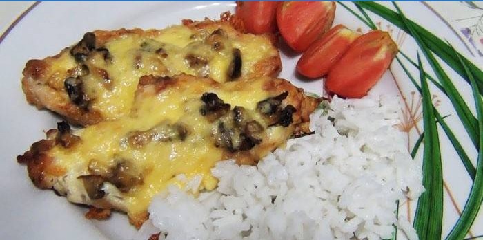 Hotové kotlety so šampiňónmi a syrom a varenú ryžu na tanieri
